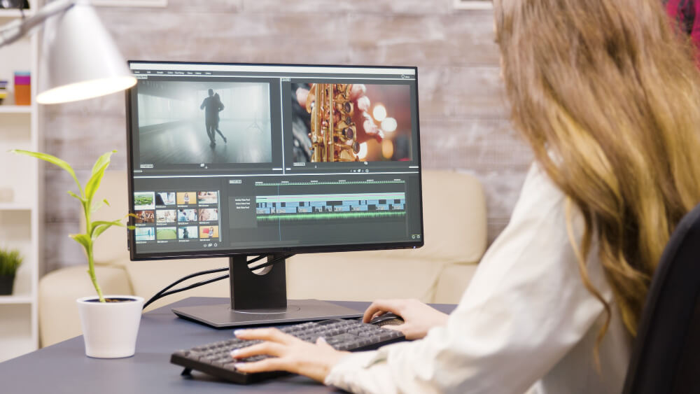 A blonde woman is editing vidoes on a computer