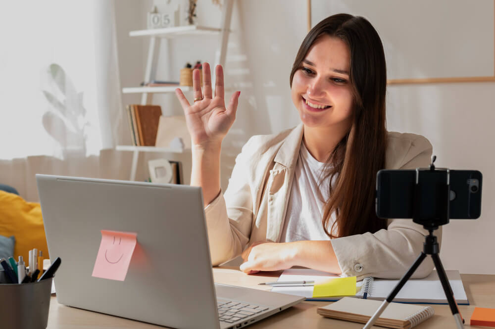 A smiling girl is saying hello to the laptop